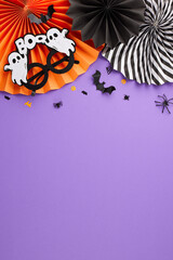 Wishing you a hauntingly good time at Halloween party. Top view vertical flat lay of folding paper fans, ghost-shaped eyewear, halloween decorations on purple background with space for ad or text