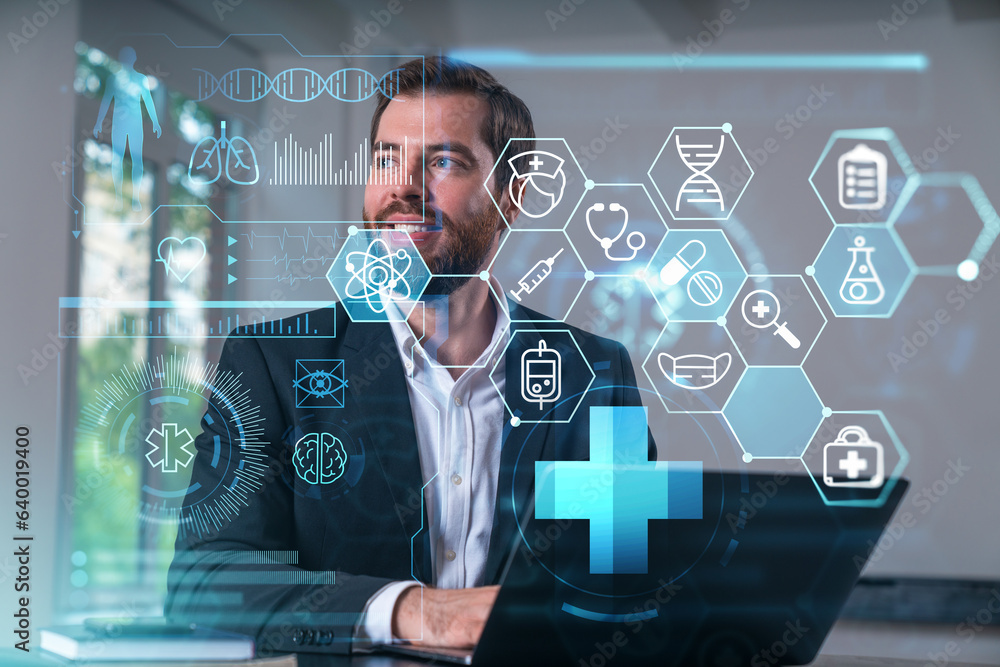 Fototapeta premium Smiling businessman in formal wear working on laptop at office workplace with smartphone and notebooks. Concept of successful business deal, agreement. Medical healthcare icons.