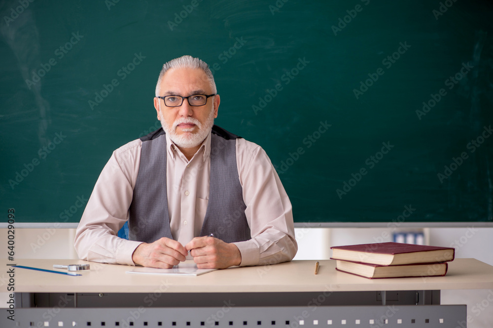 Old male teacher in the classroom Old male teacher in the classroom
