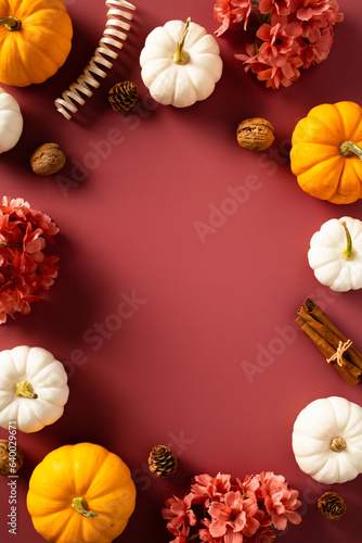 Autumn, fall vertical banner design with ripe pumpkins, flowers, cinnamon sticks, walnuts, pine cones on dark red background.