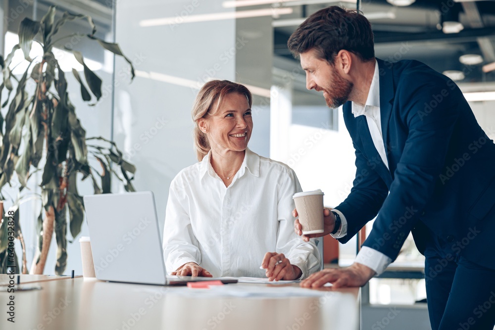 © Yaroslav Astakhov - Happy mature female boss discussing project with employee that showing presentation