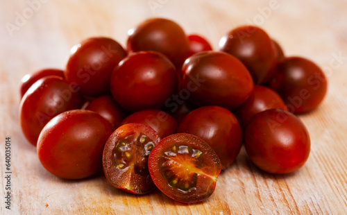 Closeup of fresh ripe kumato tomatoes on wooden surface. Organic vegetables concept photo