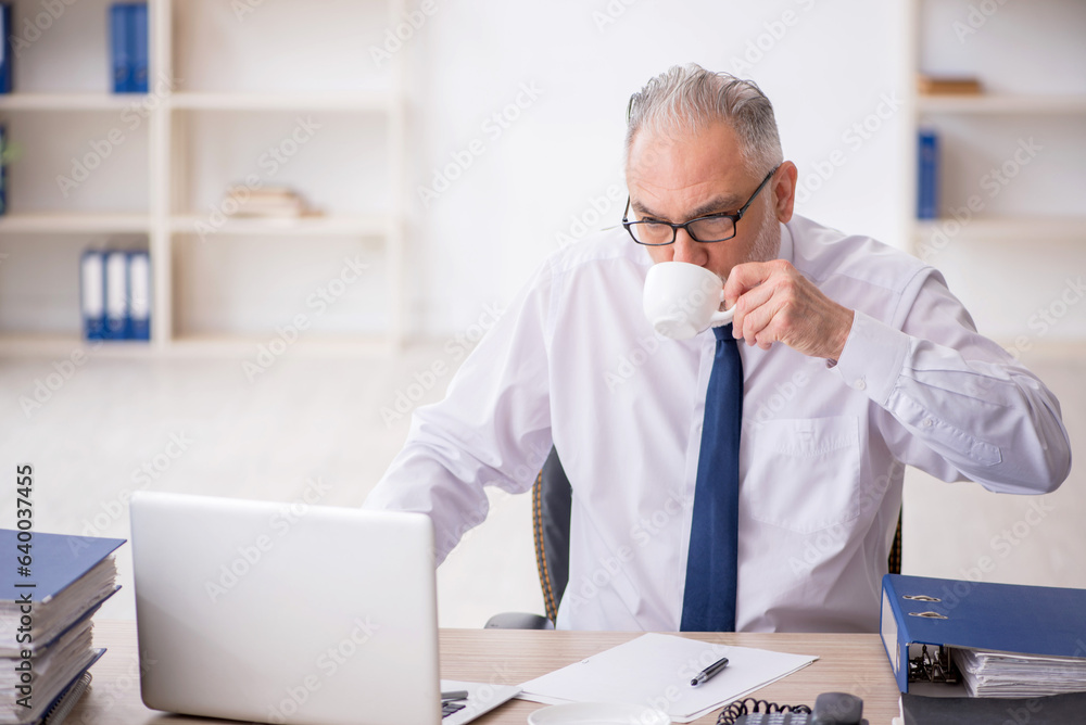 Fototapeta premium Old male employee drinking coffee during break