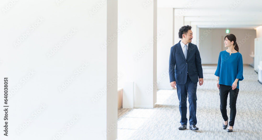 オフィスの通路を移動するビジネスパーソン コピースペースあり オフィスの通路を移動するビジネスパーソン コピースペースあり