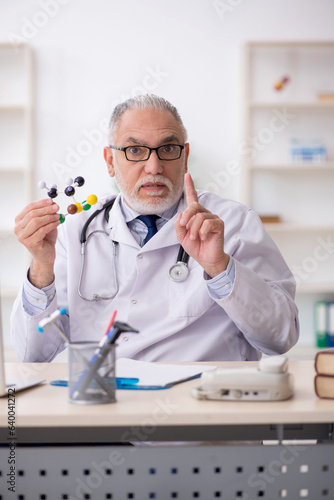 Old male doctor holding molecular model