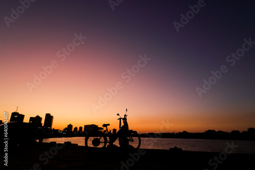 Campos dos Goytacazes, RJ, Brazil, 08/19/2023 - Woman and child with a bike in silhouette at sunset © Giampaolo