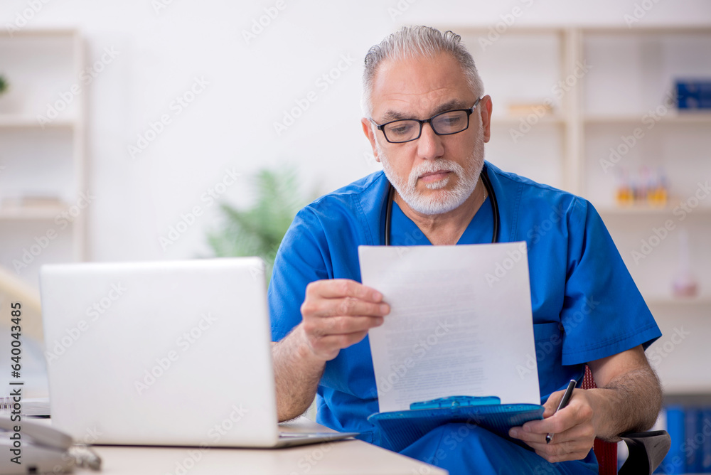 Old male doctor working in the clinic Old male doctor working in the clinic