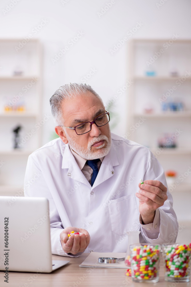 Old male doctor suggesting pills in the clinic Old male doctor suggesting pills in the clinic