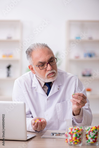 Old male doctor suggesting pills in the clinic
