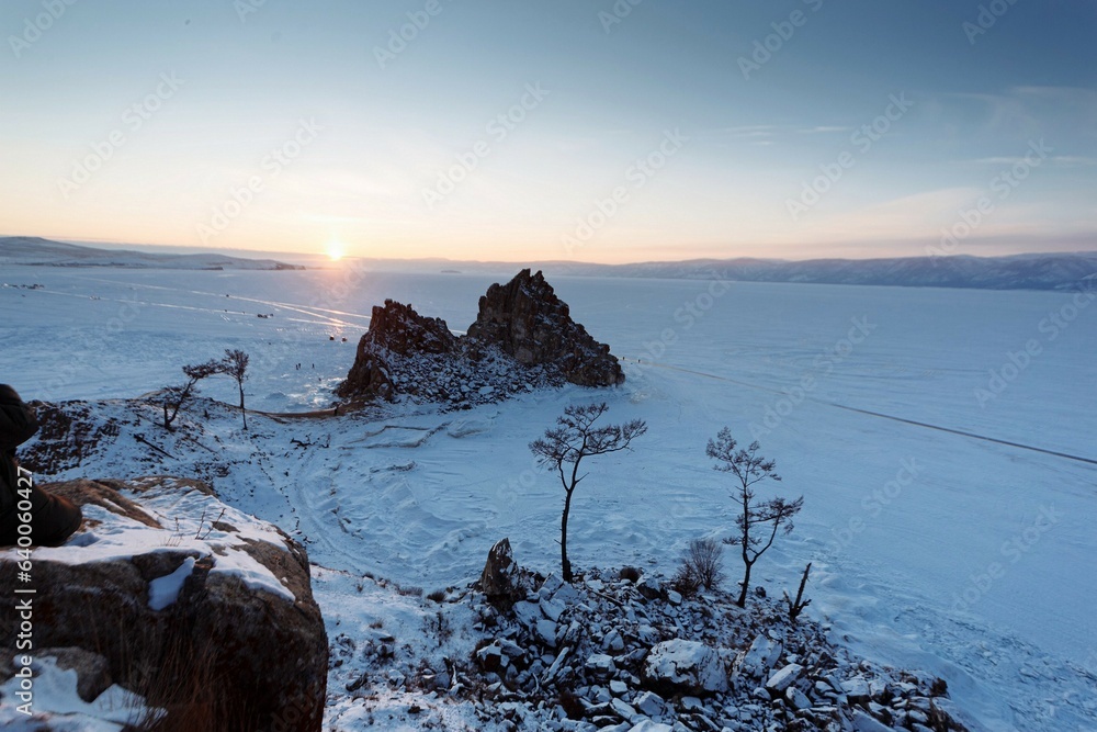 The Shamanka Rock and Beach Bay in the lights of sunset. Winter Baikal lake