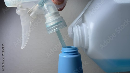 Male hands fill up hand sanitiser blue alcohol to foggy sprayer bottle close up view