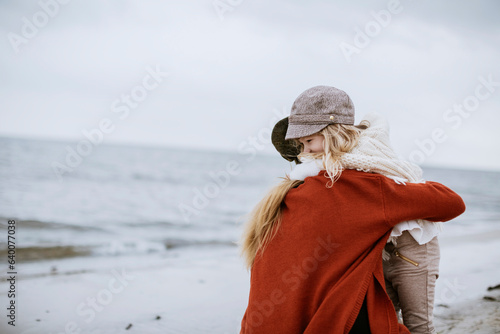 Fototapeta Mother and daughter walking on a beach during winter