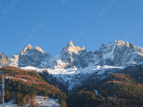 Scenic view of white snowcapped mountain peaks in Charmonix, French Alps, France, Europe. Snowy summits and dark green coniferous trees hill and blue winter sky. Chamonix Needles chain near Mont Blanc © Chris