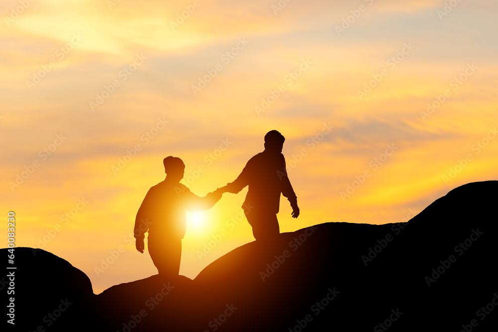Silhouette of a couple holding hands and walking together with blurred sunset background, Teamwork couple climbing helping hand