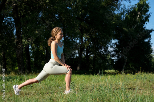 Young woman doing exercises, stretching before sport training on a park. Summer sunny day outdoor for active life