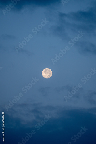 Full moon photo with some clouds during blue hour
