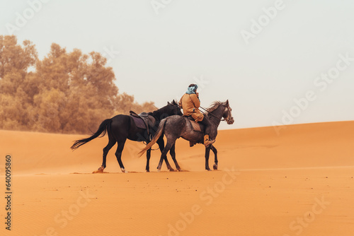 Moroccan berber man with horses through the sahara desert in Merzouga, Morocco