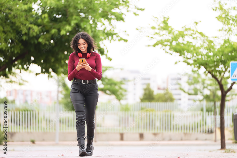 Woman smiling while using her mobile phone walking outdoors. Technology concept. Woman smiling while using her mobile phone walking outdoors. Technology concept.