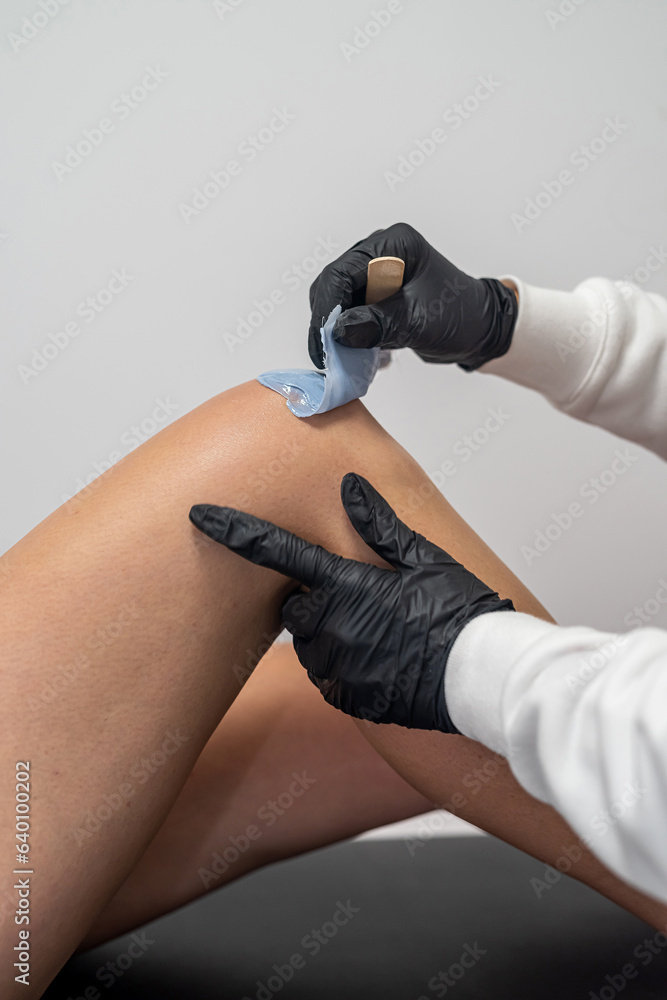 Depilation of a woman's legs with sugaring in the salon is done by a master.