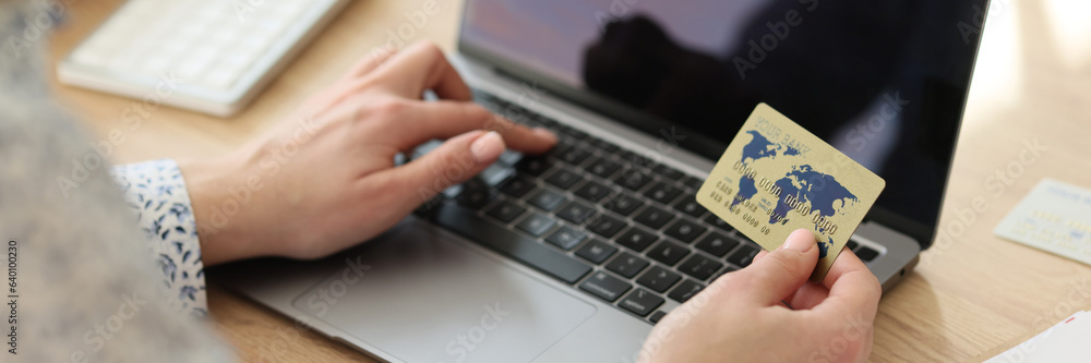 A woman dials credit card number on a laptop keyboard A woman dials credit card number on a laptop keyboard