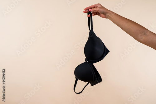 woman hand holding black bra in her hand isolated on light background
