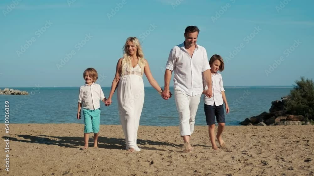 A happy family with a pregnant mother are walking along the ocean. A happy family with a pregnant mother are walking along the ocean.