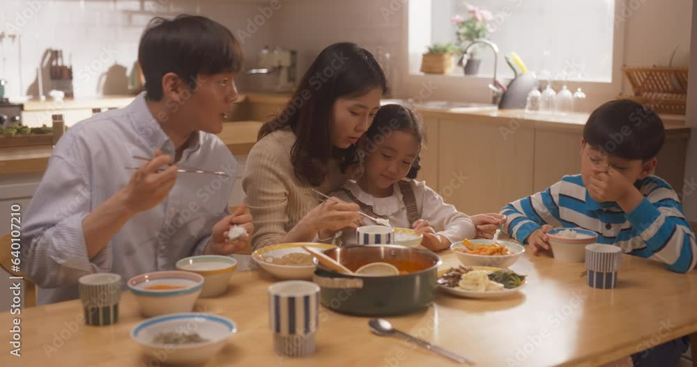 Happy Korean Family of Four Enjoying a Delicious Meal Together in Their Kitchen at Home. Parents and Their Cute Children Gathered For Lunch, Eating and Talking While Sitting at the Table Happy Korean Family of Four Enjoying a Delicious Meal Together in Their Kitchen at Home. Parents and Their Cute Children Gathered For Lunch, Eating and Talking While Sitting at the Table