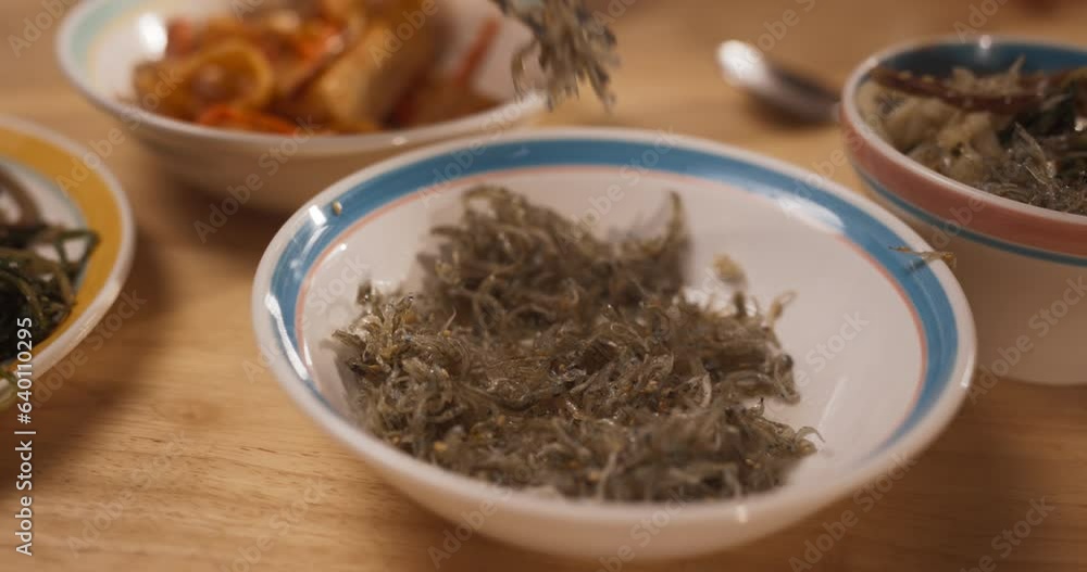 Close up on Vegan Korean Side Dish: Anonymous People Using Metal Chopsticks to Pick Up Seaweed Stem. Vegetarian Asian Food on a Dining Table. Family Sharing Delicious Food and Having Good Time Close up on Vegan Korean Side Dish: Anonymous People Using Metal Chopsticks to Pick Up Seaweed Stem. Vegetarian Asian Food on a Dining Table. Family Sharing Delicious Food and Having Good Time