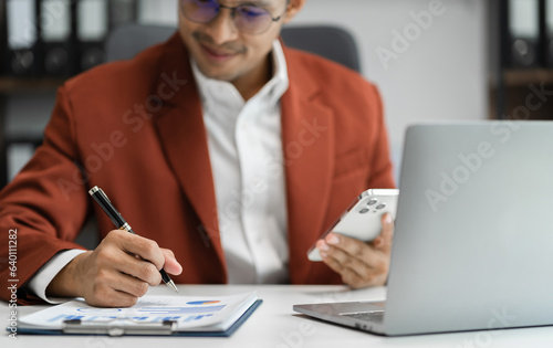 Business man using digital tablet analyzes business data, busy working on laptop computer with smart phone and business report on office desk, business strategy analysis concept.