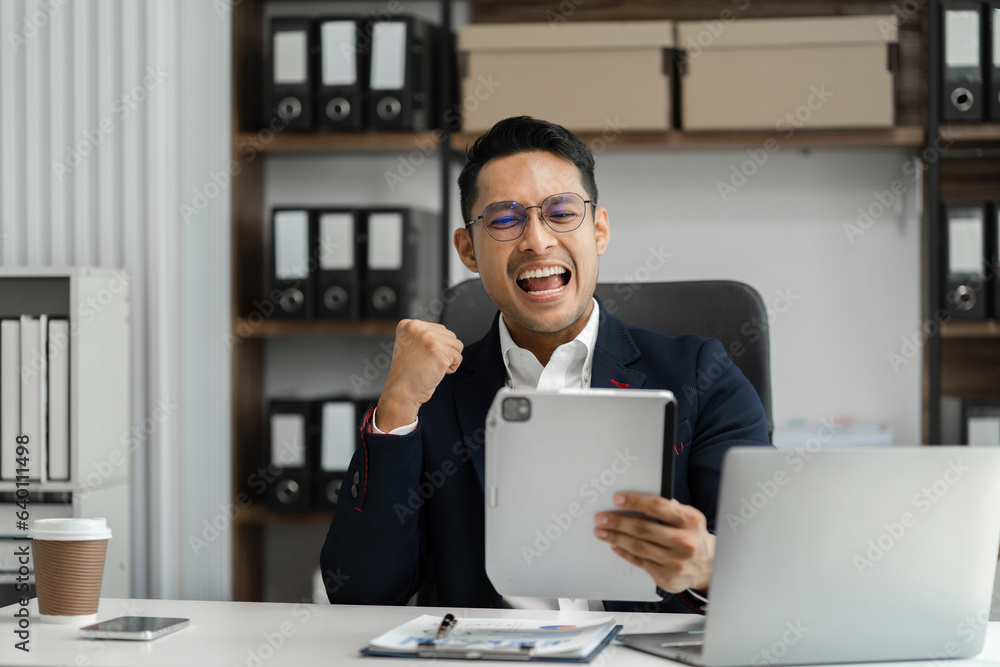 Successful young male excited business success with inspiration from their excellent financial results that are happy working in a modern office on a tablet. Successful young male excited business success with inspiration from their excellent financial results that are happy working in a modern office on a tablet.