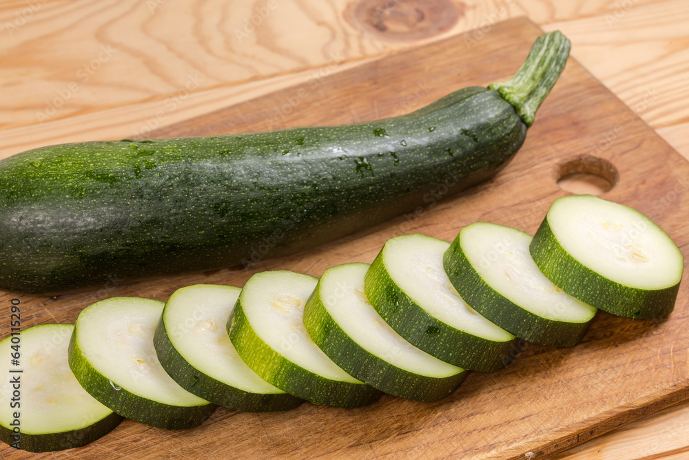 Whole and sliced dark green zucchini on the cutting board Whole and sliced dark green zucchini on the cutting board