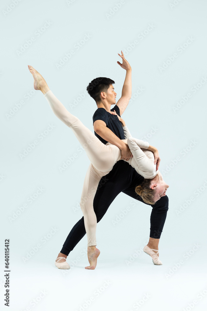 Obraz premium Ballet Concepts. Asian Young Man and Caucasian Woman Performing As Ballet Dancers Over Grey in Studio During Suppots As Classical Dance Aesthetics With Choreography Art