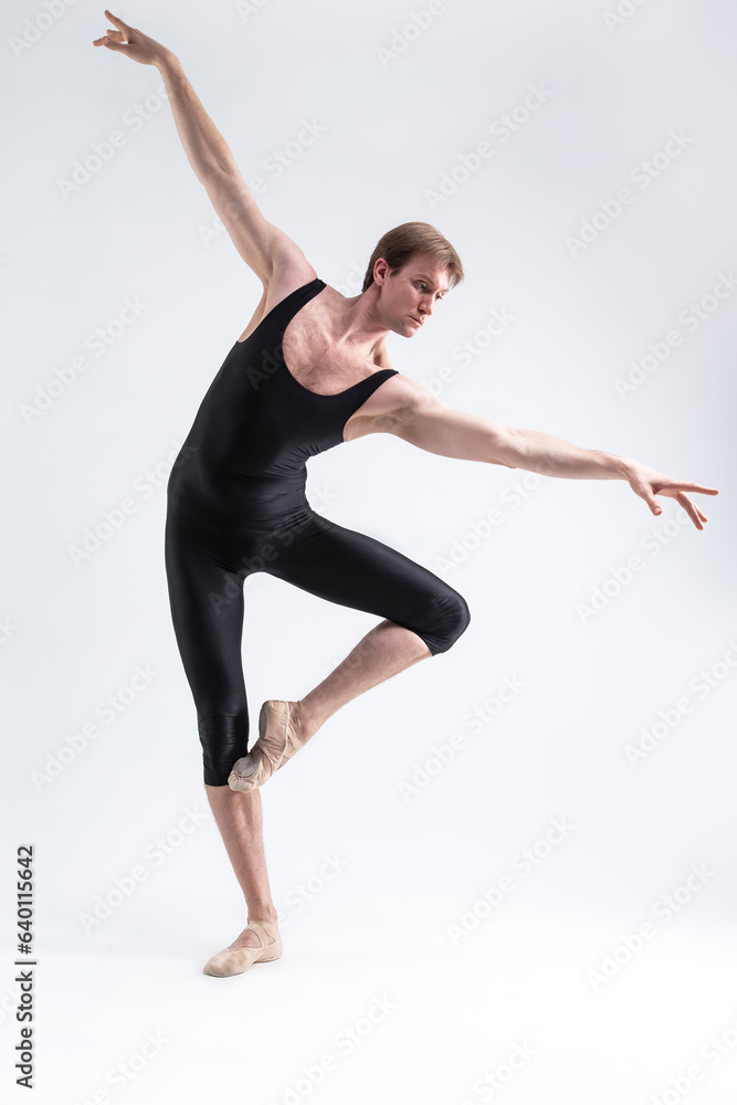 Obraz premium Ballet Dancer Man Posing in Dancing Stretching Pose With Hands Lifted While Standing in Ballance in Black Tights On White.
