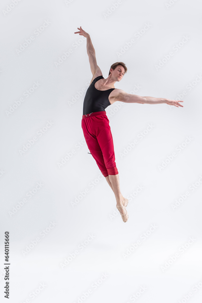 Naklejka premium Modern Ballet Dancer. Contemporary Art Ballet With Young Flexible Athletic Man Posing in Flying Dance Pose in Studio on White