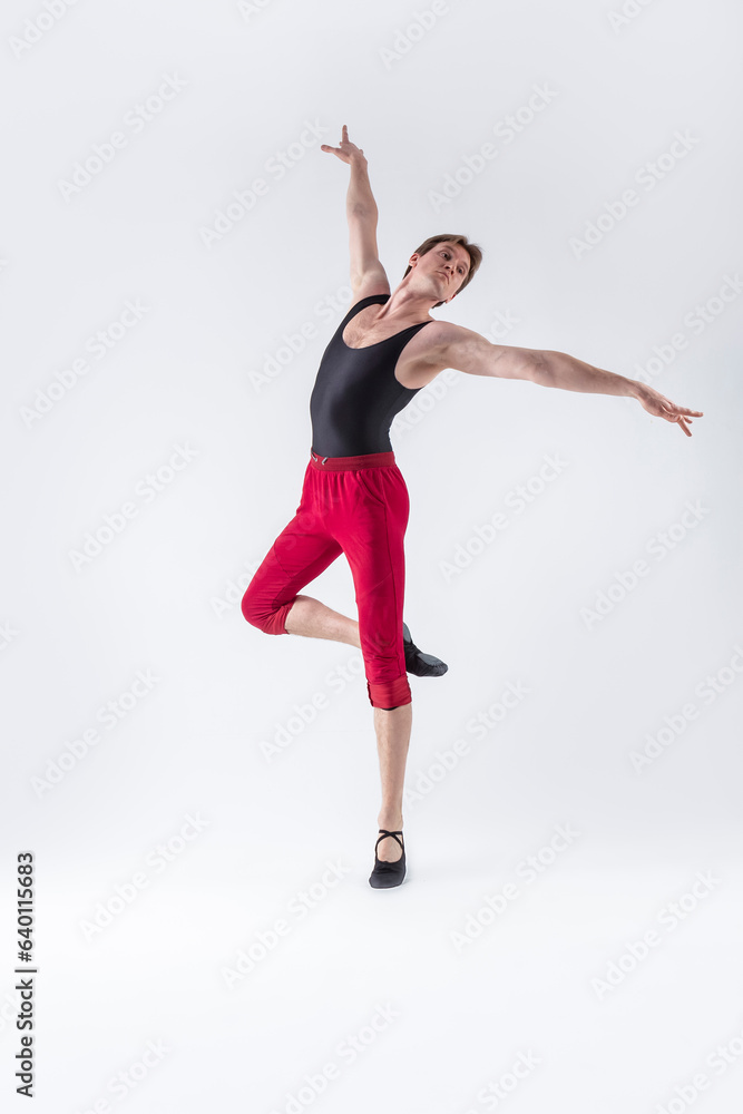 Fototapeta premium Ballet Ideas. Contemporary Ballet of Flexible Athletic Man Posing in Red Tights in Dance Pose With Hands Lifted in Studio on White.