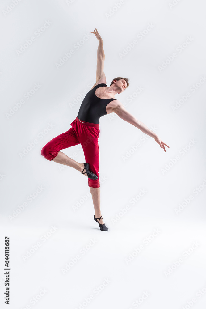 Ballet Ideas. Modern Ballet of Flexible Athletic Man Posing in Red Tights in Ballanced Dance Pose With Hands Lifted in Studio on White. Ballet Ideas. Modern Ballet of Flexible Athletic Man Posing in Red Tights in Ballanced Dance Pose With Hands Lifted in Studio on White.