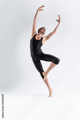Fototapeta Naklejka Na Ścianę i Meble -  Professional Male Ballet Dancer Young Athletic Man in Black Suit Posing in Ballanced Dance Pose Studio On White.