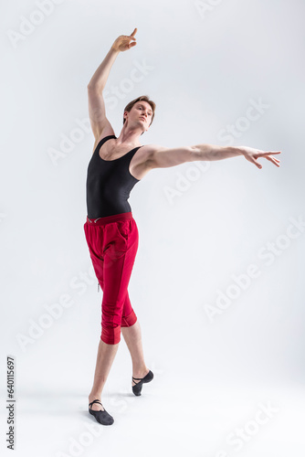 Stretching of Concentrated Contemporary Ballet Dancer Flexible Athletic Man Posing in Red Tights in Ballanced Dance Pose With Hands Lifted