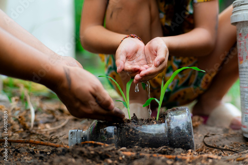Little girl and mom grow plants in pots from recycled water bottles in the backyard. Recycle water bottle pot, gardening activities for children. Recycling of plastic waste photo