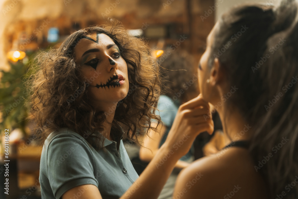Halloween party preparations, female friends checking face paint for costume Halloween party preparations, female friends checking face paint for costume