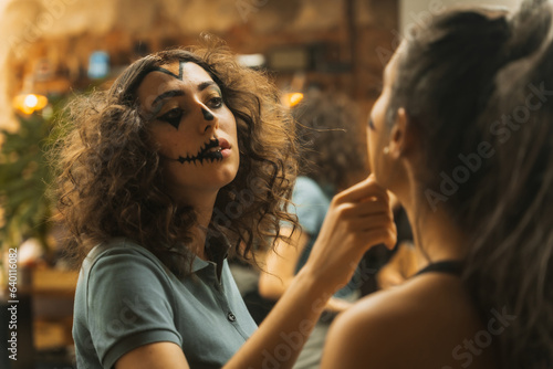 Halloween party preparations, female friends checking face paint for costume