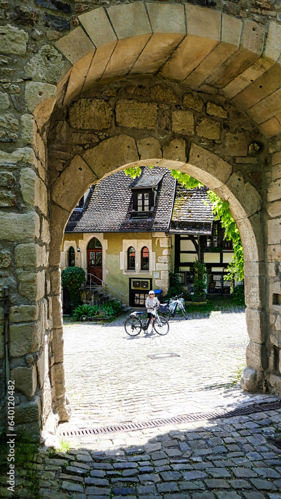 Blick durch einen Torbogen mit einer Radlerin im Kloster Bebenhausen im Schönbuch