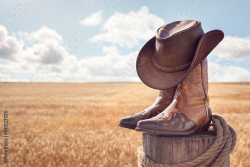 Cowboy hat, boots and wheat field background at ranch stables, country music festival live concert or line dancing concept