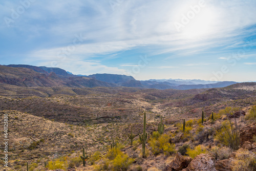 Filtered through high clouds, the sun washes over the rocky, cactus-strewn desert terrain of the Tonto National Forest in Arizona. Shot from Route 88, also known as the Apache Trail.