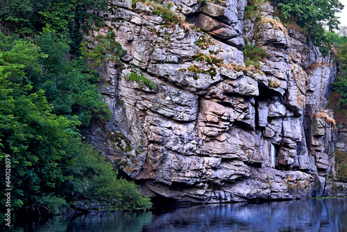 Deep rocky stone canyon with smoothly flowing water, greenery