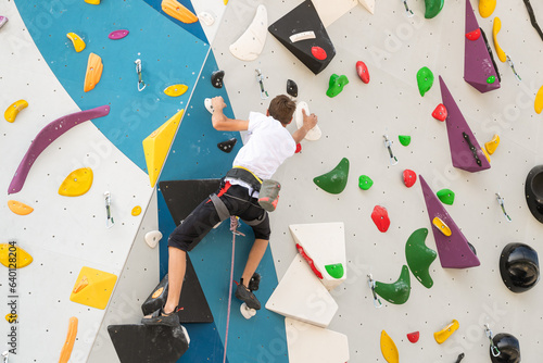 Foto A climber climbs an artificial stone wall using a harness
