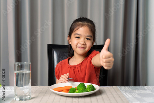Cute little girl showing thumb showing eating healthy vegetables.