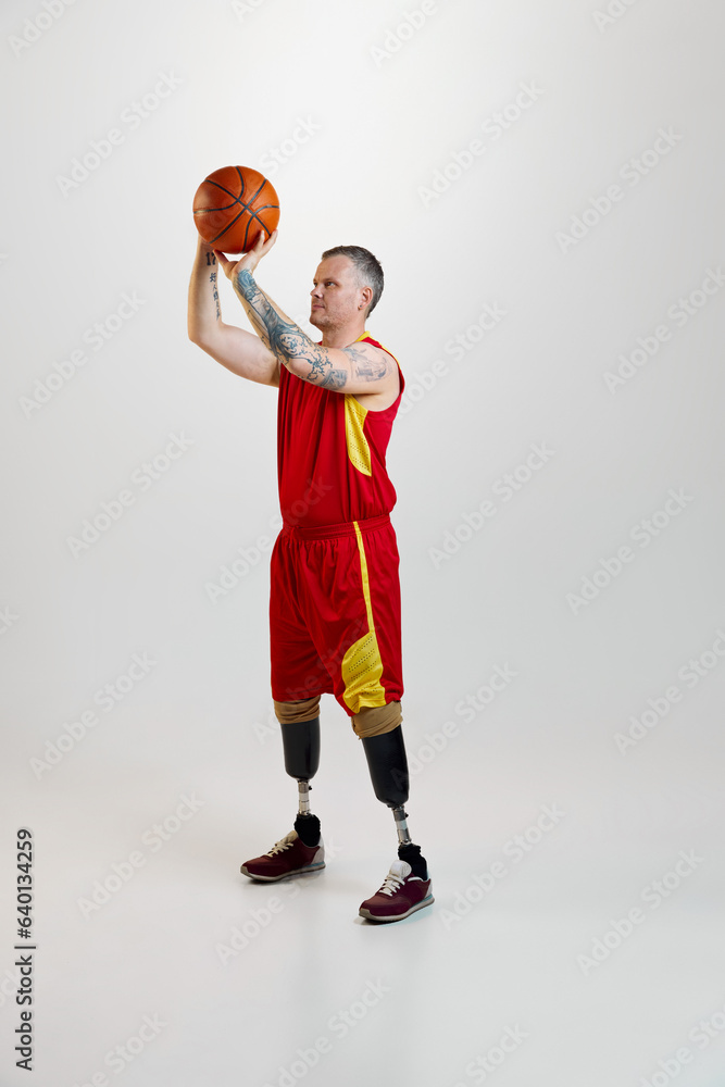 Attractive, confident, sporty man with prosthetic legs, disability in uniform with basketball ball in motion. Inclusive sport for people with disabilities.
