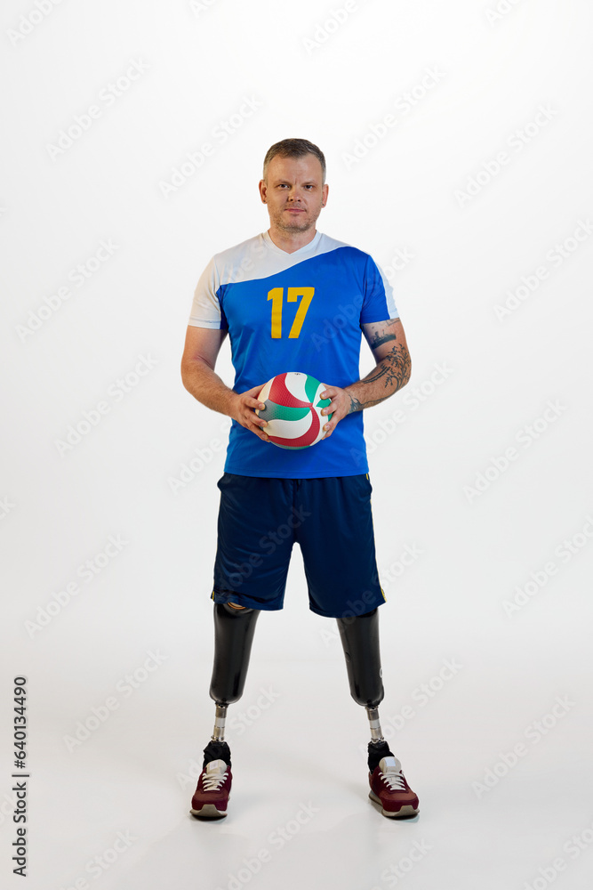 Attractive young man with prosthetic leg disability standing holding volleyball ball. Inclusive sport for people with disabilities.