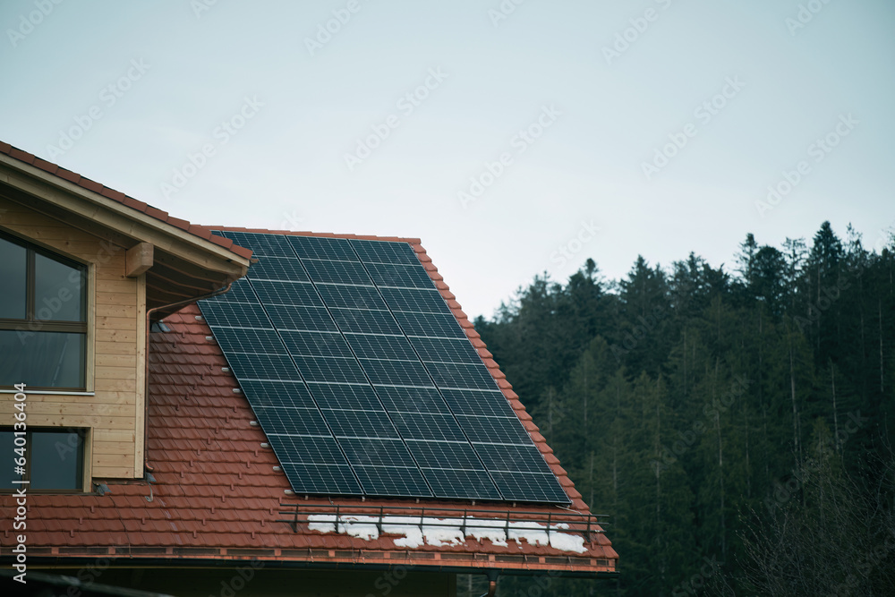 Fototapeta premium House with solar panels. Photovoltaic panels PV on the sky background. Blue solar panels. An alternative source of electricity.